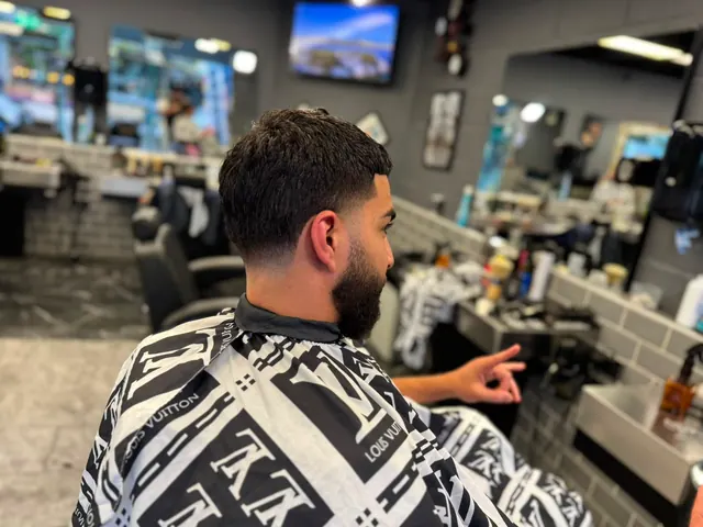 A bearded client talking with his barber from the chair