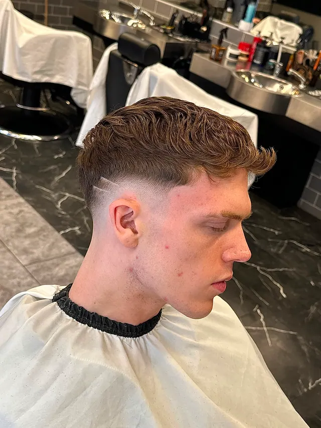 A textured crop with a skin fade and a cut-in part line, side view