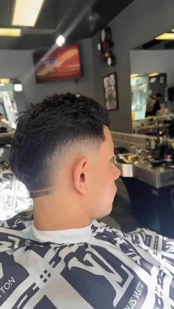 A skin fade with a cut-in part line, finished in the chair